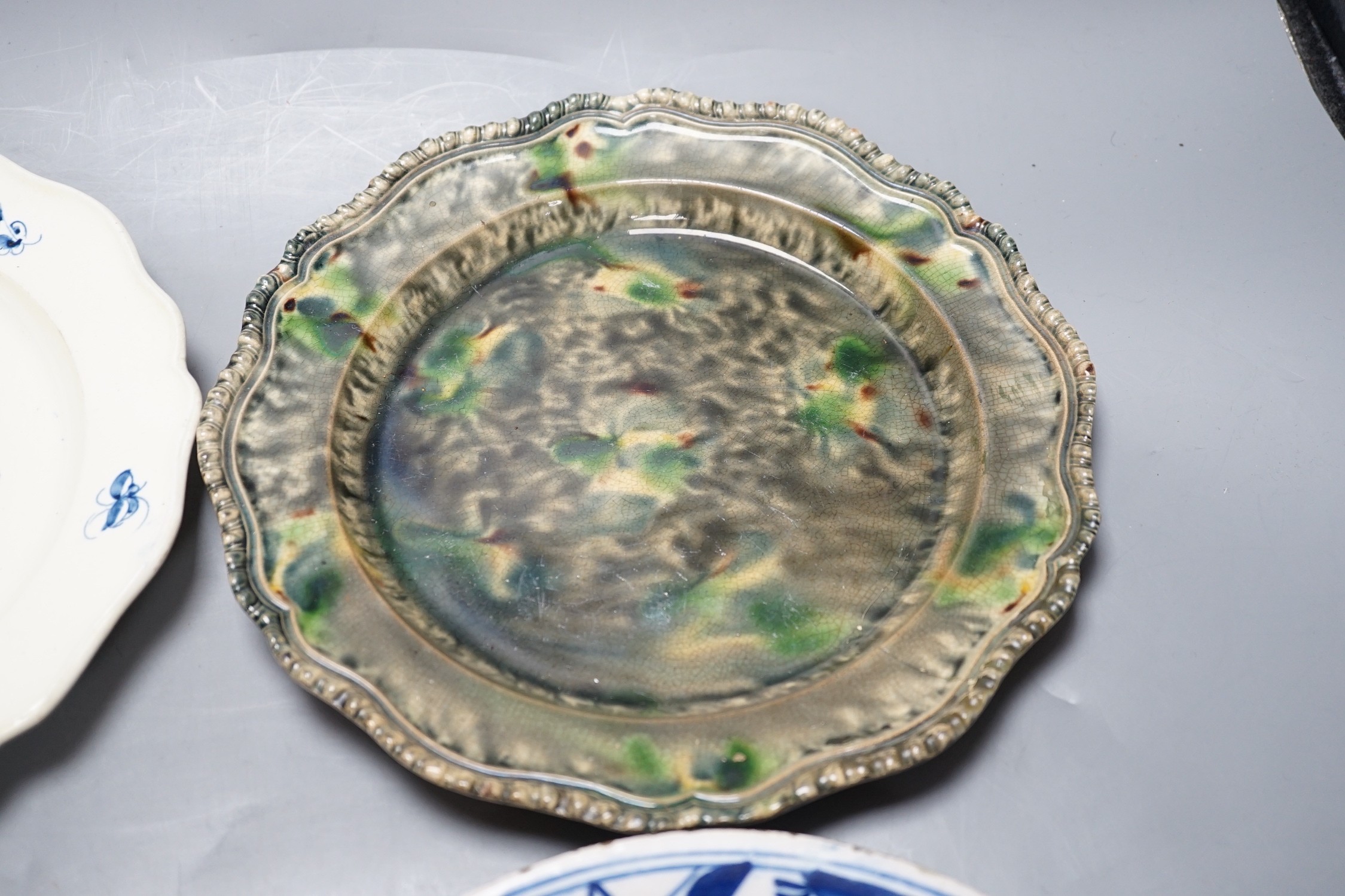 A Staffordshire salt glaze plate with pierced border, a Staffordhire tortoiseshell painted plate, a creamware underglaze blue plate and a Dutch delft plate, salt glazed plate 21 cms diameter